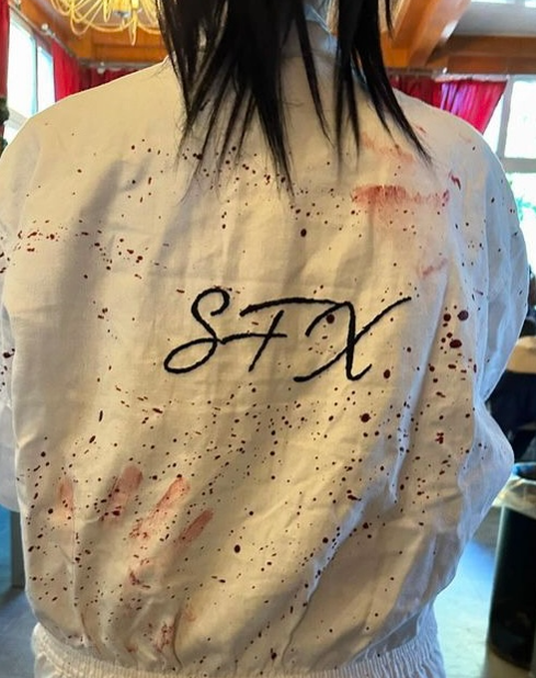 Photo d’une combinaison de maquilleur FX portant l’inscription SFX dans le dos, tachée de faux sang sur un plateau de tournage