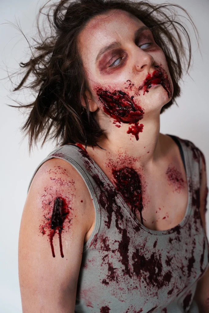 Maquillage SFX effet zombie avec peau déchirée et prothèse faciale pour un shooting photo d'effets spéciaux.