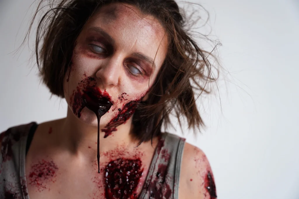 Maquillage SFX effet zombie avec peau déchirée et prothèse faciale pour un shooting photo d'effets spéciaux.